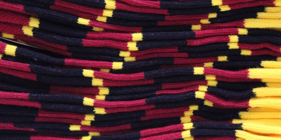A close-up of dozens of folded navy, deep pink and yellow socks stacked in overlapping rows.